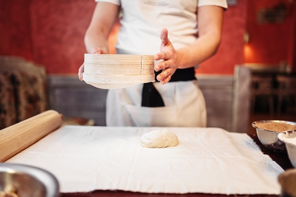 male person works with dough on wooden kitchen table homemade strudel cooking - Постный штрудель с яблоками, орехами, изюмом и корицей