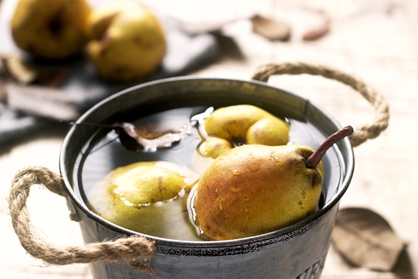 ripe pears and pear leaves in an iron bucket with water and on a wooden table rustic style - Варенье из груш с корицей