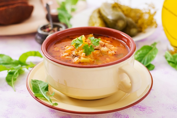 soup with pickled cucumbers and pearl barley rassolnik on a light table - Консервированная заправка для рассольника