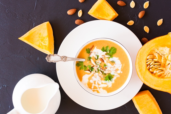 healthy eating dietary vegetable soup from pumpkin in a plate with parsley on a black background top view - Молочный суп с тыквой и миндалём