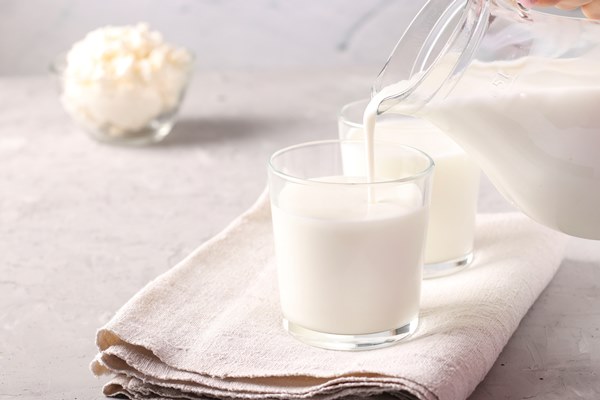 kefir or ayran fermented drink is poured into a glass from a jug as well as cottage cheese in a bowl on a light gray surface copy space close up - Калитки карельские