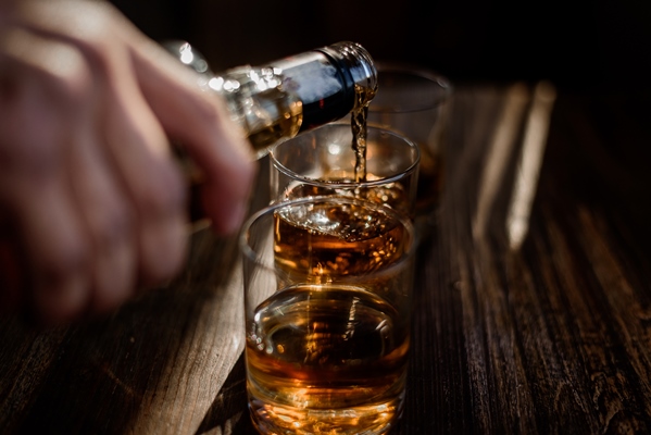 pouring strong alcohol drink into the glasses which are on the wooden table - Печенье "Хворост"