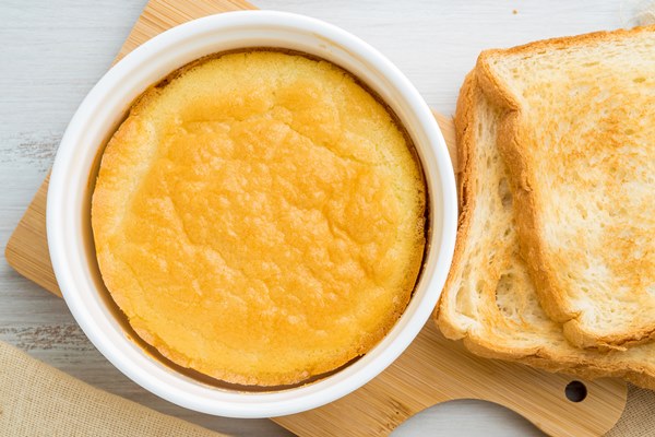 white round ramekin with oven baked omelet of eggs and milk with a crust on white wooden - Драчена миндальная с ванилью