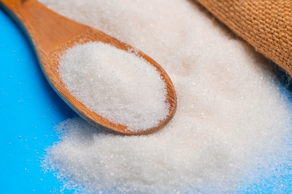 white sugar sand in a wooden spoon on a blue background - Драчена миндальная с ванилью