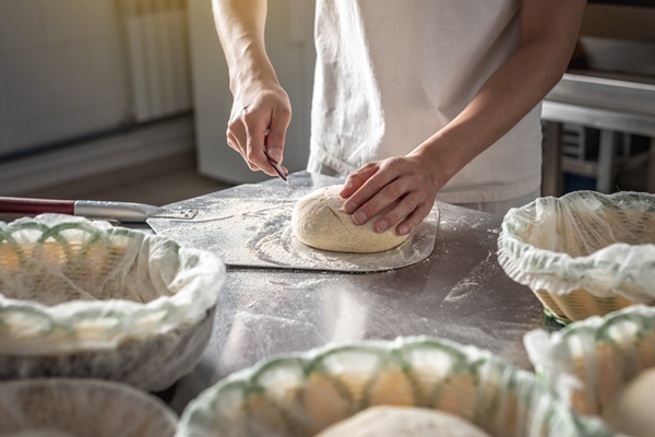 baker cuts the dough with a knife before going into the oven for baking production of bakery products - Бородинский хлеб