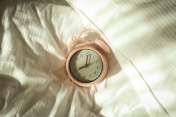 pink alarm clock on the bed in the morning - Напиток от бессонницы "Банановый чай"