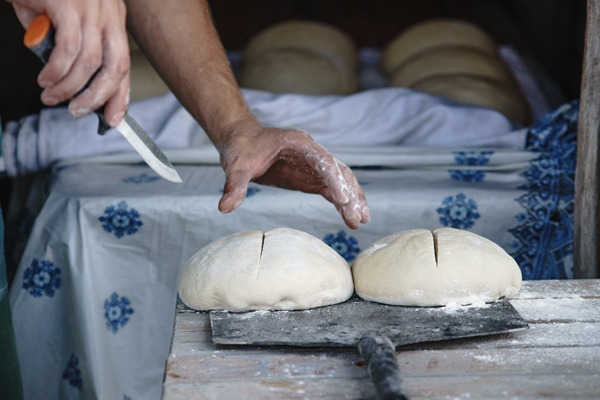 the baker prepares the dough for baking bread in a rural oven ukrainian village - Украинский хлеб