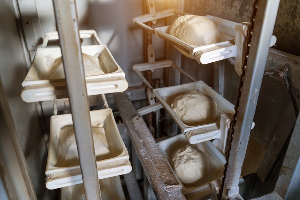 the dough for baking bread moves along the conveyor in closeup - Ржаной кислый хлеб