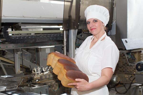 the worker of the plant for the production of bread with bread in her hands bread factory with a worker - Ржаной кислый хлеб