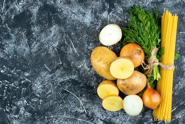 top view of raw pasta with potatoes parsley and onions on light gray surface - Разварной картофель с жареным луком и макаронами