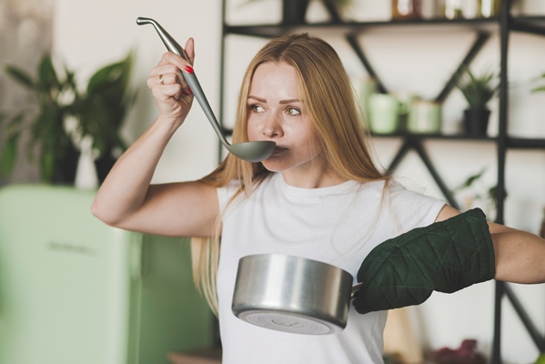 blonde young woman tasting soup from the ladle - Супы: срок годности