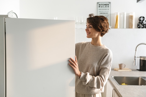 happy young woman standing at the opened fridge - Супы: срок годности