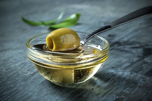 olive oil and olive branch on the wooden table - Использование оливок в кулинарии