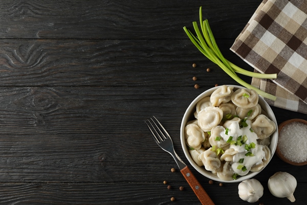 bowl with dumplings towel fork and spices on wooden background top view - Пельмени