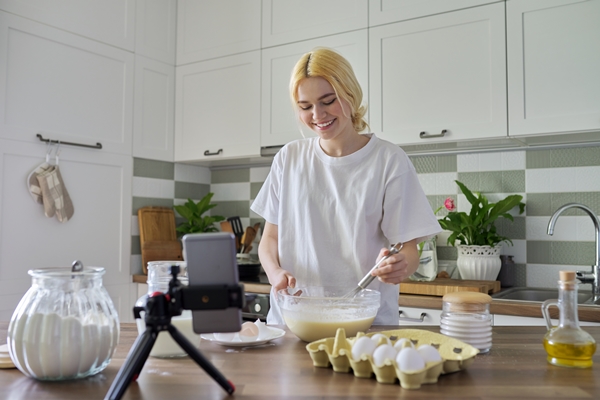 female teenager learns to cook pancakes watching video recipe on smartphone - Блинцы тонкие заварные на кефире и яйцах