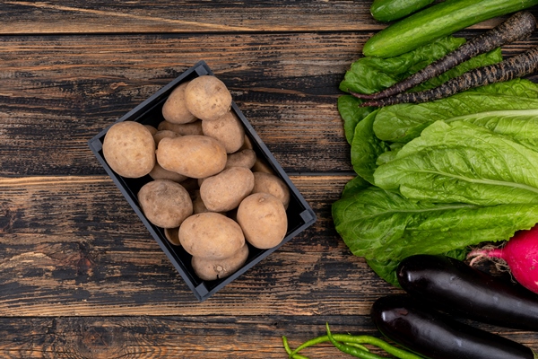 fresh potato in black basket with vegetables on wooden table - Цеппелины