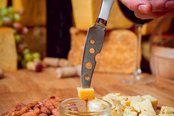 knife with piece of cheese on a dark table - Хозяйке на заметку: виды кухонных ножей