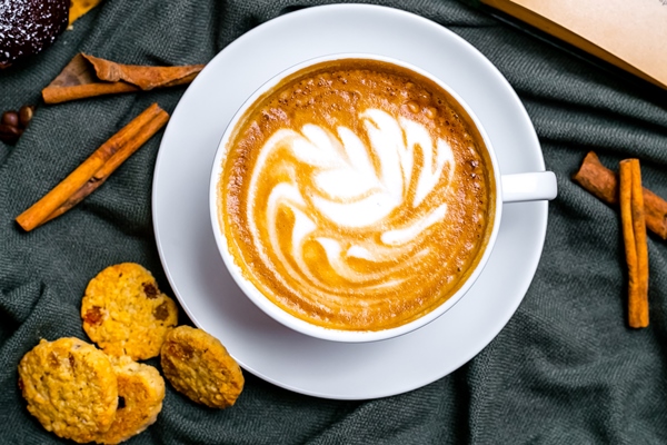 top view cup of cappuccino with cookies and a book on the table - Куркума-латте