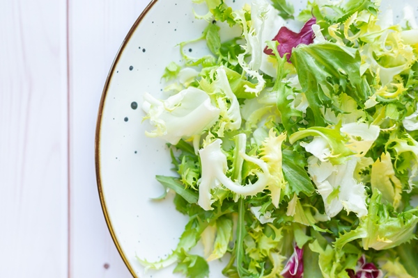 white ceramic plate with fresh salad on wooden surface - Салат с лососем и овощами