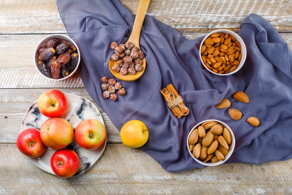 apples in a plate with cinnamon sticks dates peeled and unpeeled almonds in bowls nuts in wooden spoon top view on wooden and - Манник в мультиварке