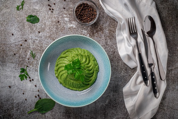 green spinach avocado cream soup blue plate with parsley dill against gray stone table - Овощная икра из шпината