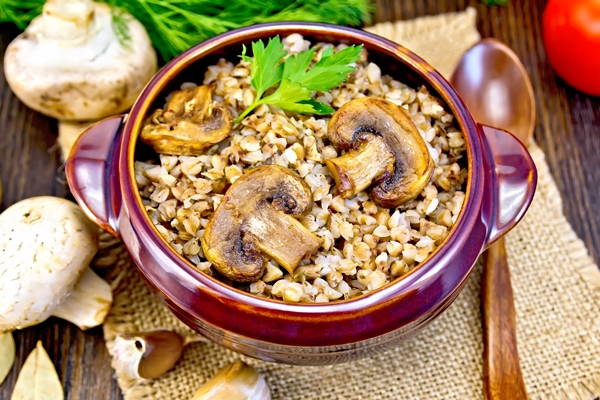 boiled buckwheat with mushrooms brown pottery bowl napkin burlap parsley tomatoes garlic dark wooden board - Гречневая постная каша на квасе