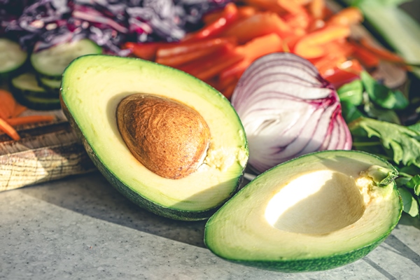 avocado halves kitchen table with chopped fresh vegetables - Как сохранить зелёный цвет нарезанного авокадо