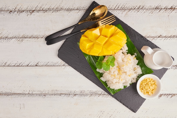 ripe mango sticky rice with coconut milk stone surface thai sweet dessert summer season - Постная рисовая каша с фруктами и растительным молоком