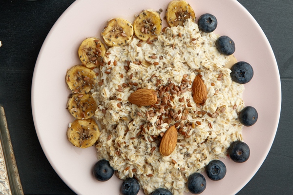 top view breakfast set with banana blackthorn flax almond oatmeal plate bowl cereal with sliced kiwi flaxseeds black background - Каша "Дружба" в мультиварке