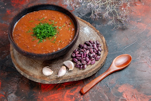 top view tomato soup beans garlic wooden cutting board spoon mix color background - Постный суп "Лобио"