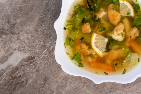 delicious soup with greens slices lemon white plate - Уха океаническая