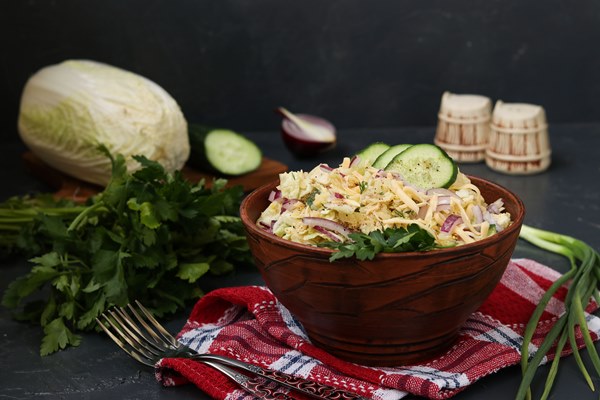 peking cabbage cucumber red onion cheese salad bowl against dark surface - Салат по коми-пермяцки