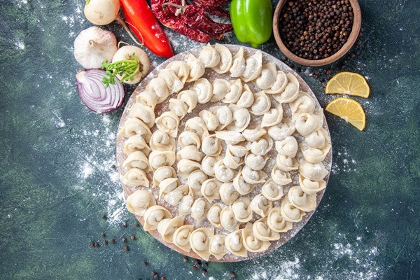 top view little raw dumplings with flour vegetables dark background meat dough food dish calorie color vegetable meal - Ушки с мясом