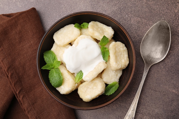 bowl tasty lazy dumplings with sour cream mint leaves brown table flat lay - Сырники варёные (старинный рецепт)