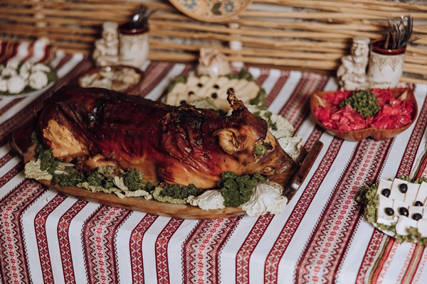 large roast pig is wooden platter table with other food items - Кесаретский поросёнок с грибами и гречкой в сметане