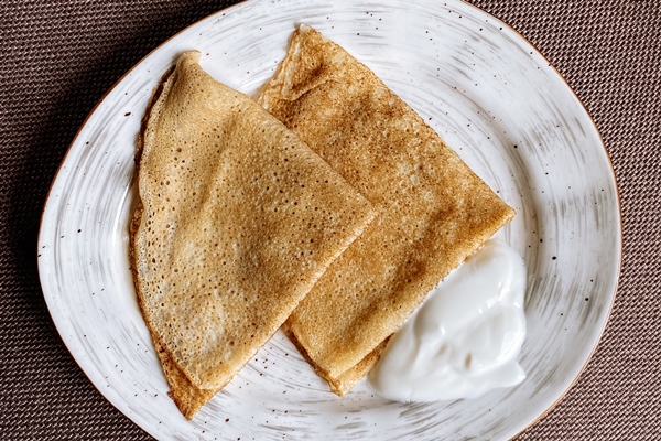 plate russian pancake with sour cream top view - Гречневые сдобные блины