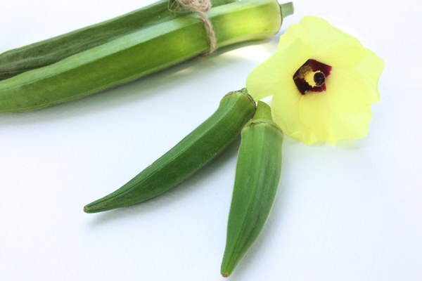 close up okras with yellow flower white table - Бамия