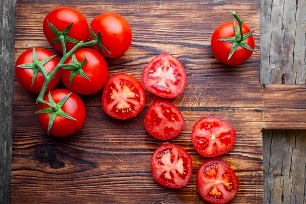 some tomatoes slices with knife wooden cutting board top view - Чем отличается томат от помидора