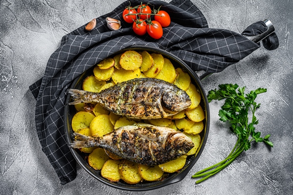 grilled dorado fish with potatoes pan gray background top view - Рыба, фаршированная икрой