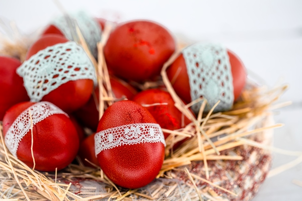 red easter eggs nest hay tied lace ribbon close up lying white wood - Как покрасить яйца пищевыми красителями