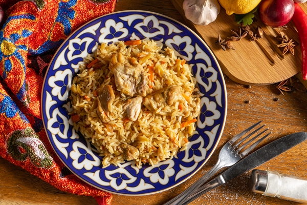 plov s kuricei tradicionnoe vostocnoe goracee bludo iz otvarnogo risa kurinogo masa ovosei i specii v tarelke s nacional nym uzbekskim ornamentom - Плов с курицей